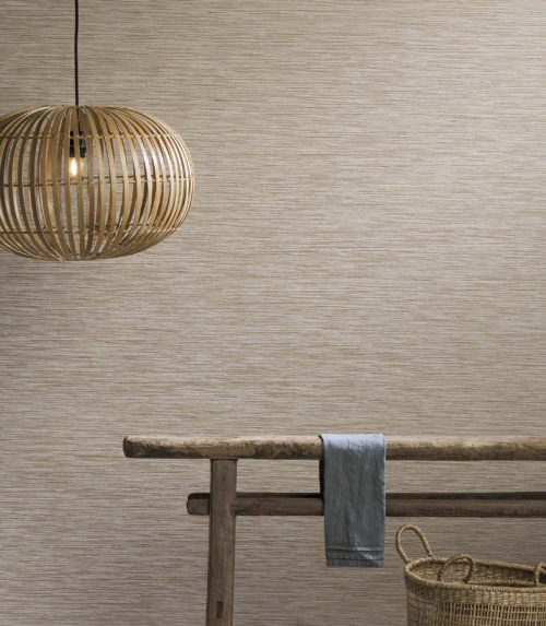 Mur habillé d'un revêtement mural Omexco Portfolio, table d'appoint en bois antique, lampe rotative, panier.